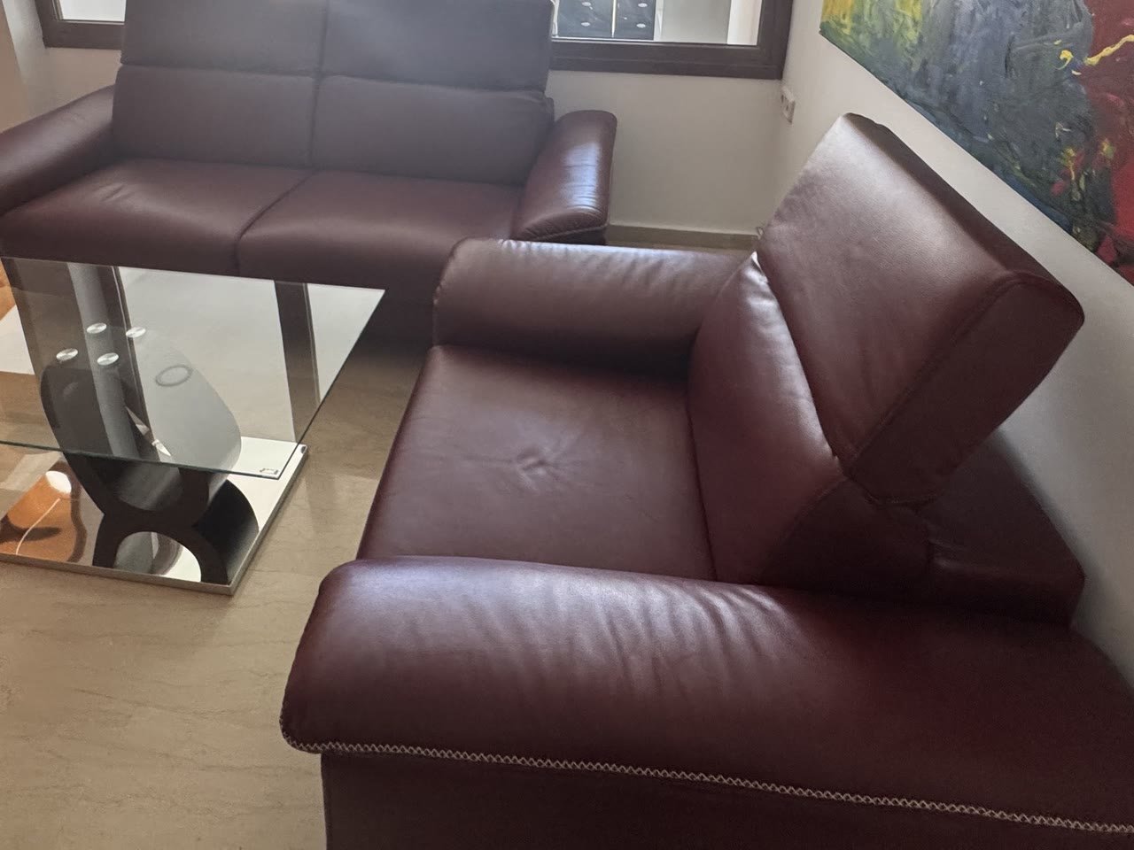 Χώρος αναμονής με μπορντό δερμάτινους καναπέδες και έργο τέχνης